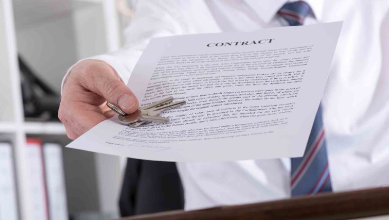 Real estate agent giving keys with contract