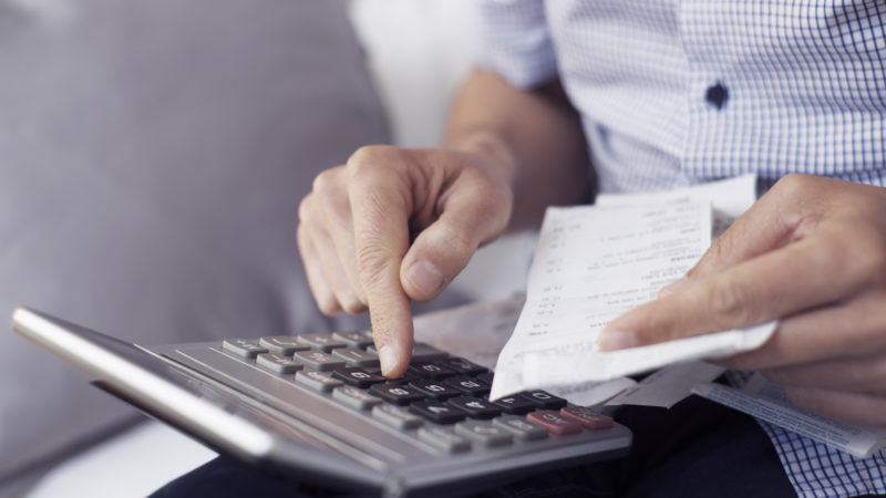 Young Man With Bills And Calculator